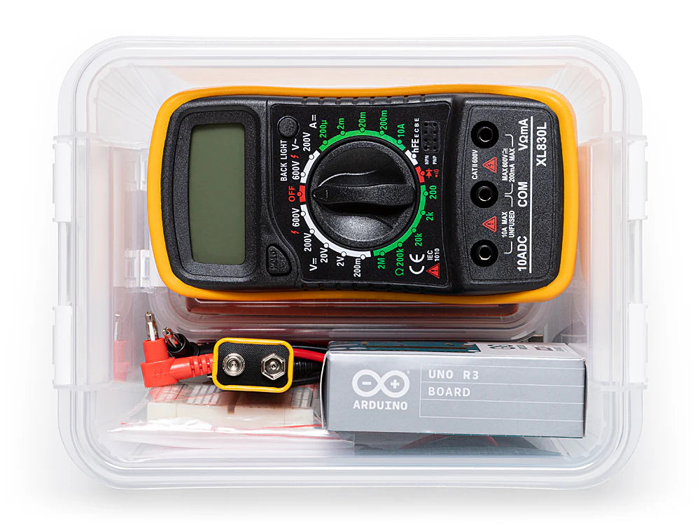 Multimeter with Arduino board and batteries in a clear plastic container on a white background